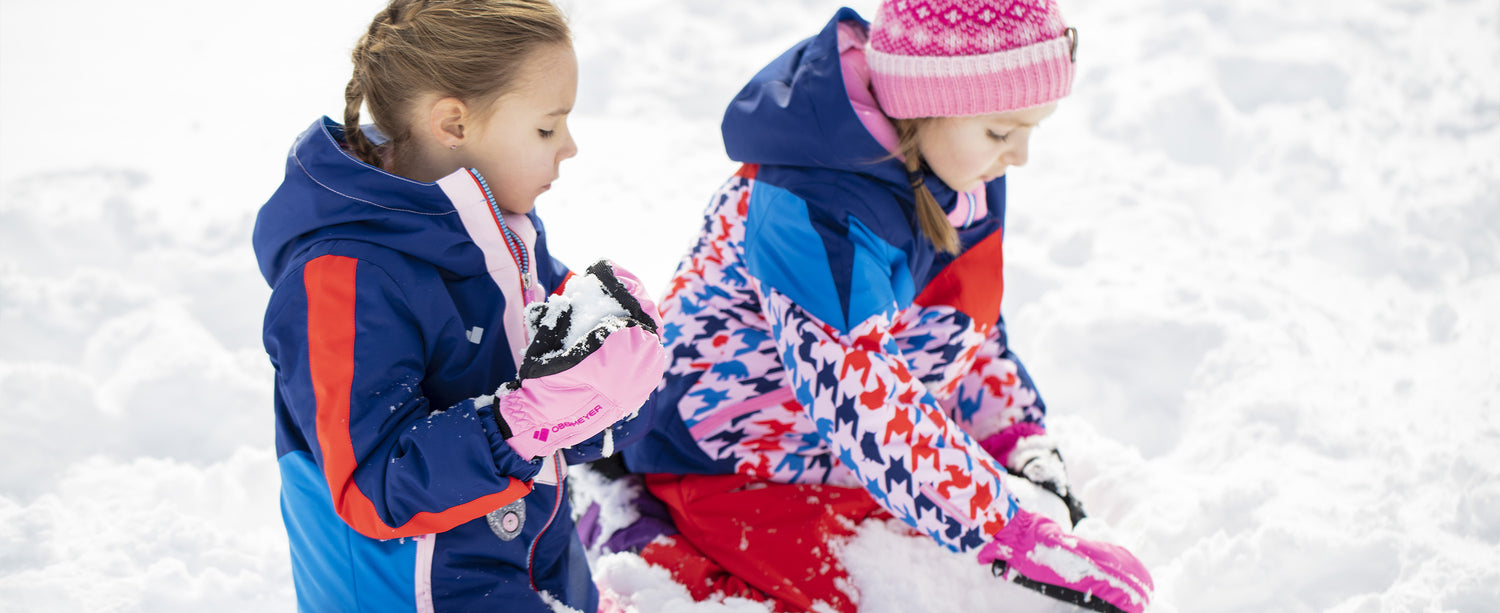 Two girls playing in the snow in Obermeyer gloves. 