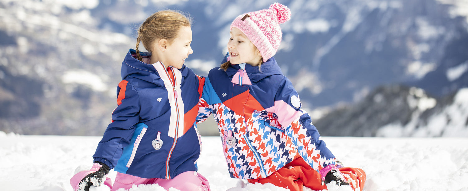 Two girls wearing Obermeyer Kid's apparel. One girl is wearing an Obermeyer beanie.