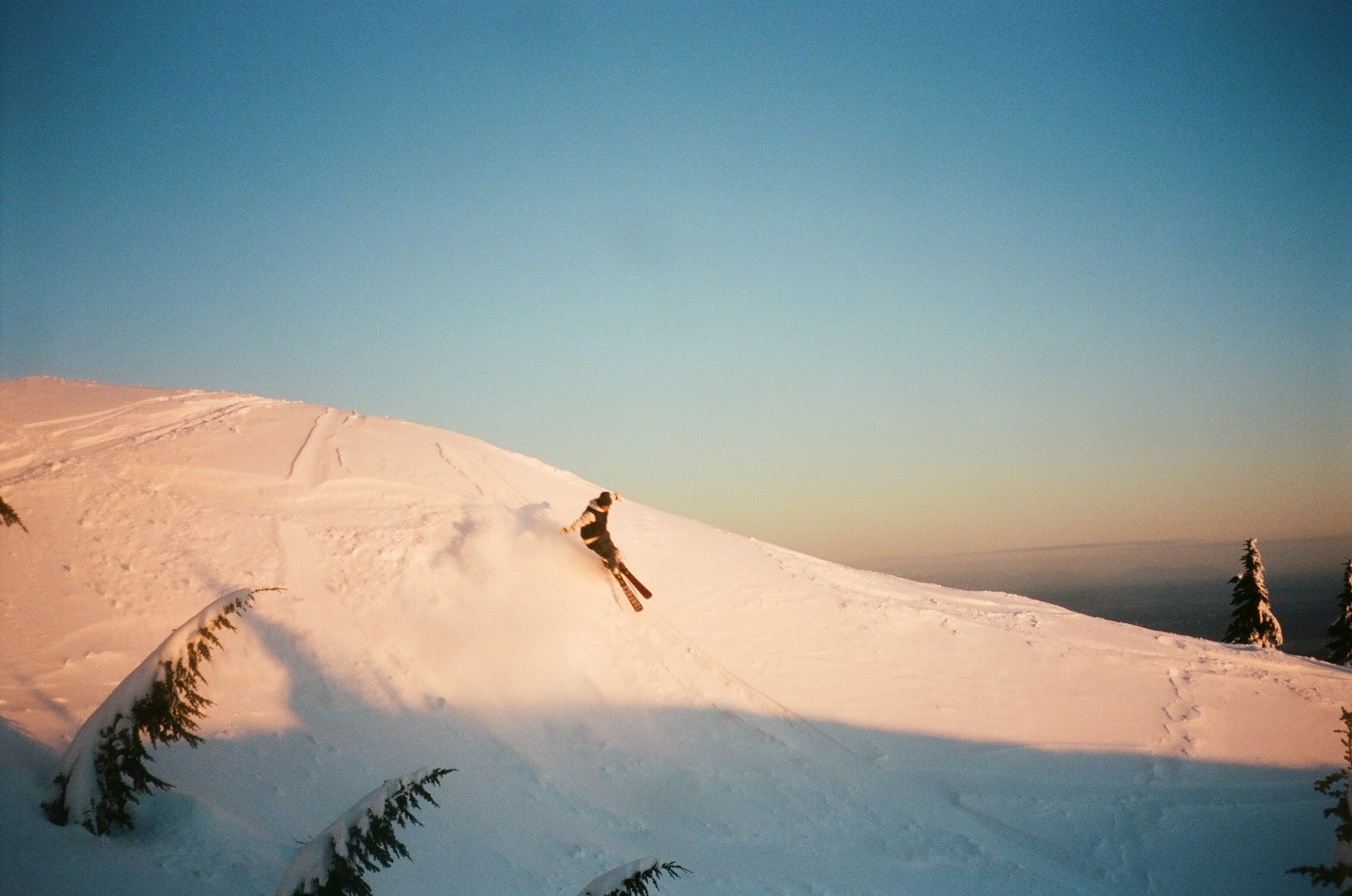 Woman skiing over a hillside on a bluebird day