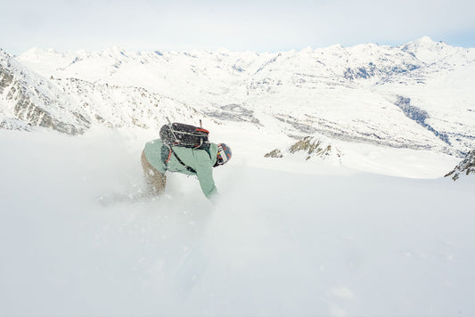 Skier carving through deep powder on a snowy mountain.