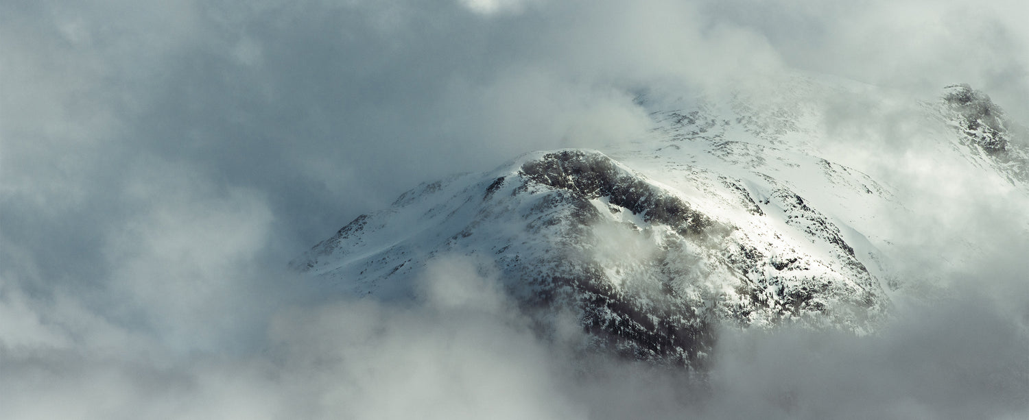 A scene of a snowy mountain surrounded by clouds.