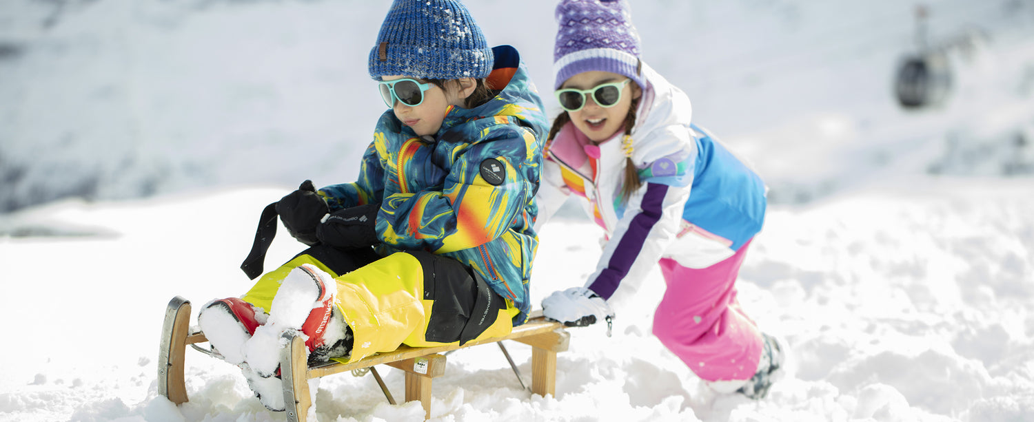 Two kids playing in the snow in Obermeyer ski apparel.