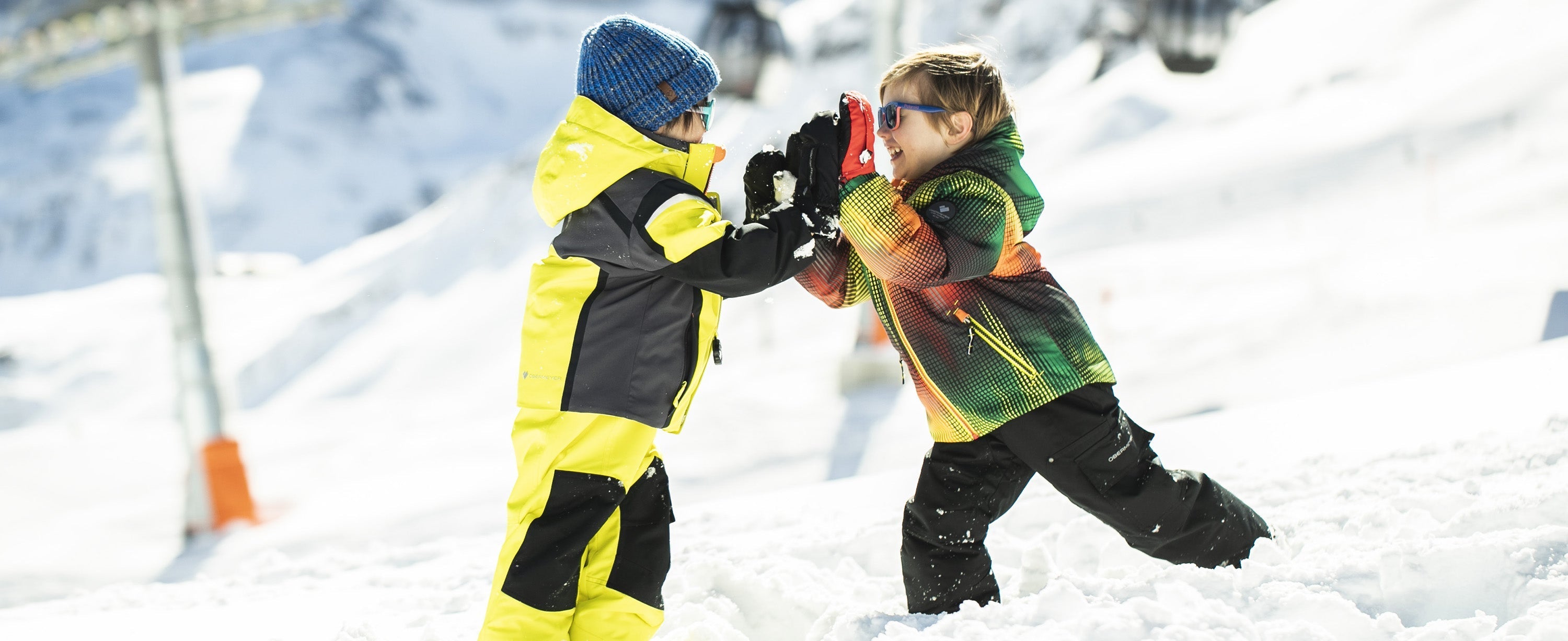 Two boys playing in the snow in Obermeyer ski apparel.