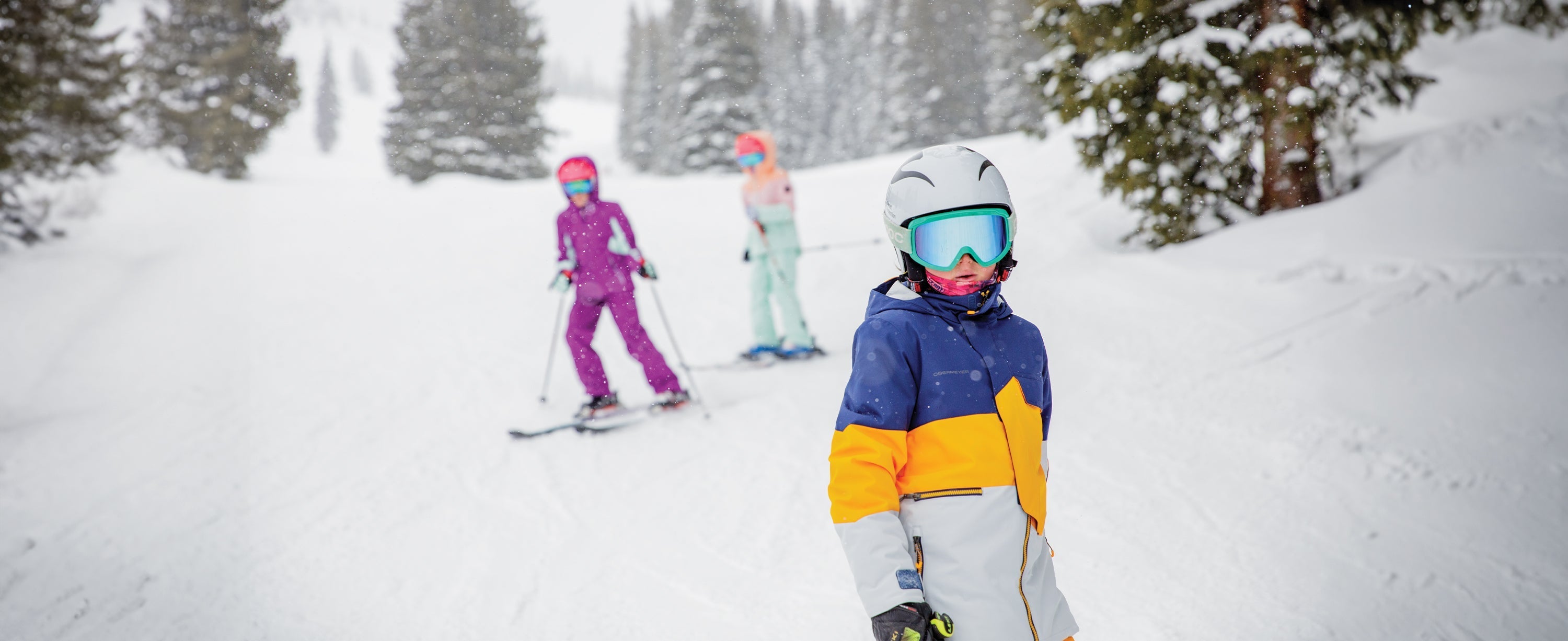 A group of teens wearing obermeyer while skiing.
