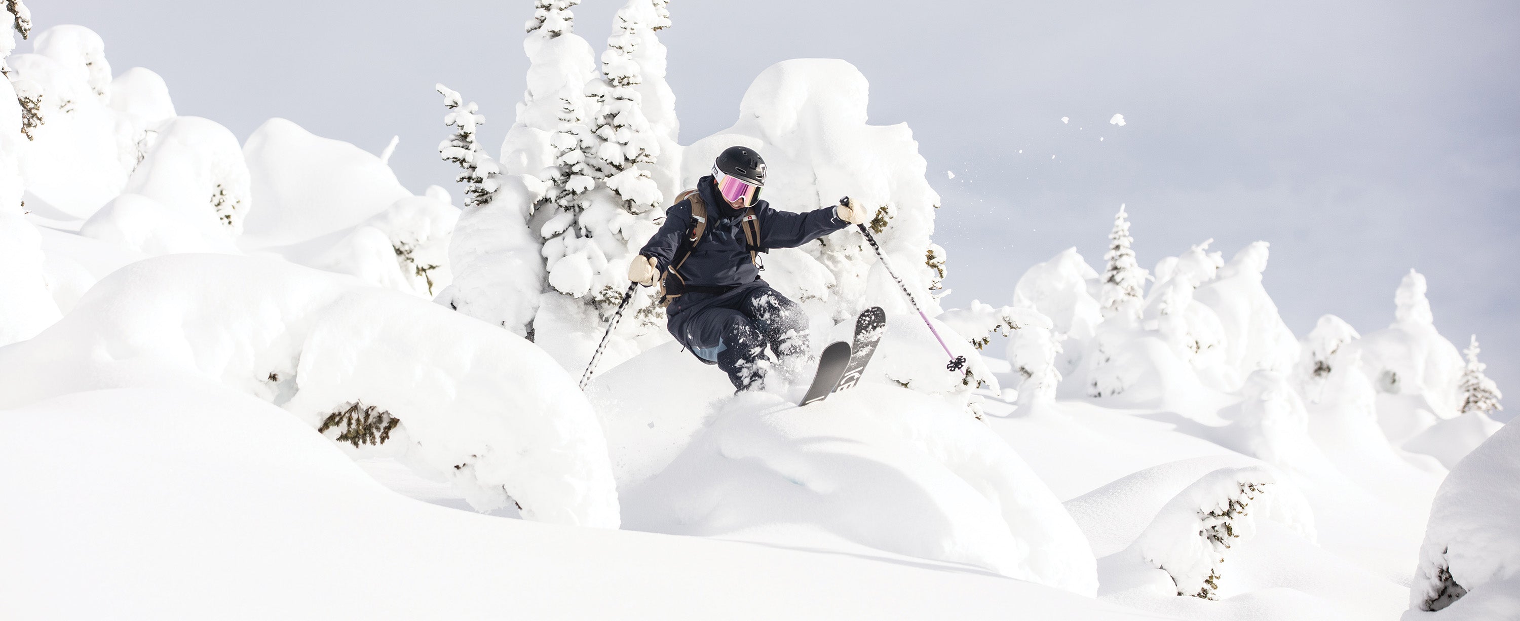 Female Skier jumping out of a tree in an Obermeyer Highlands shell kit.