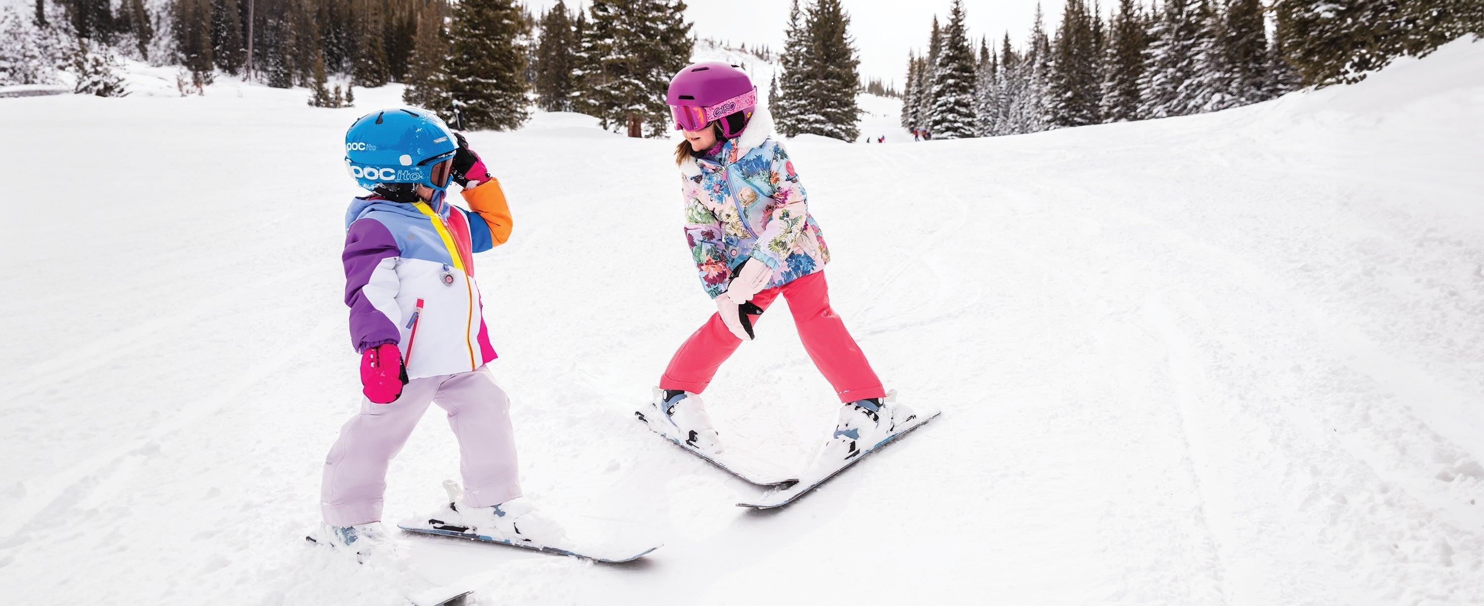 Two kid girls skiing while wearing Obermeyer.
