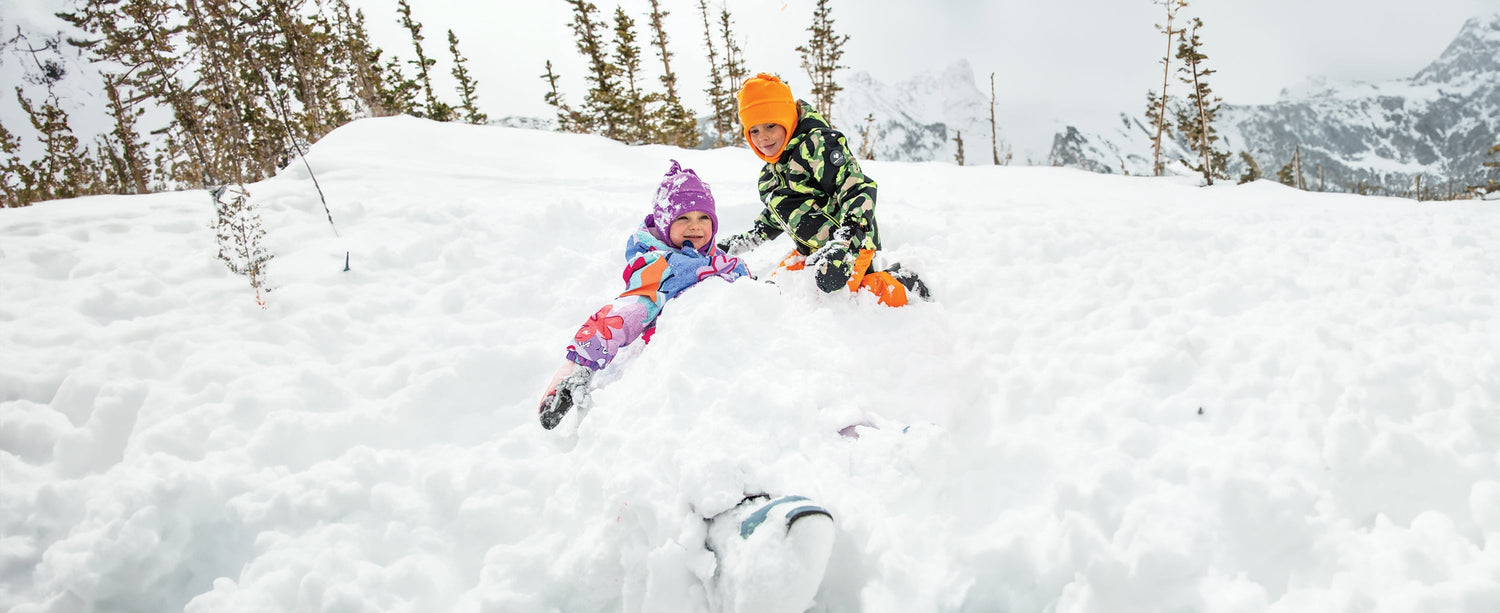 Two kids playing in the snow wearing Obermeyer.