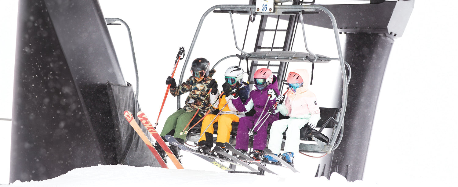 A group of teen skiers getting off of a chairlift.