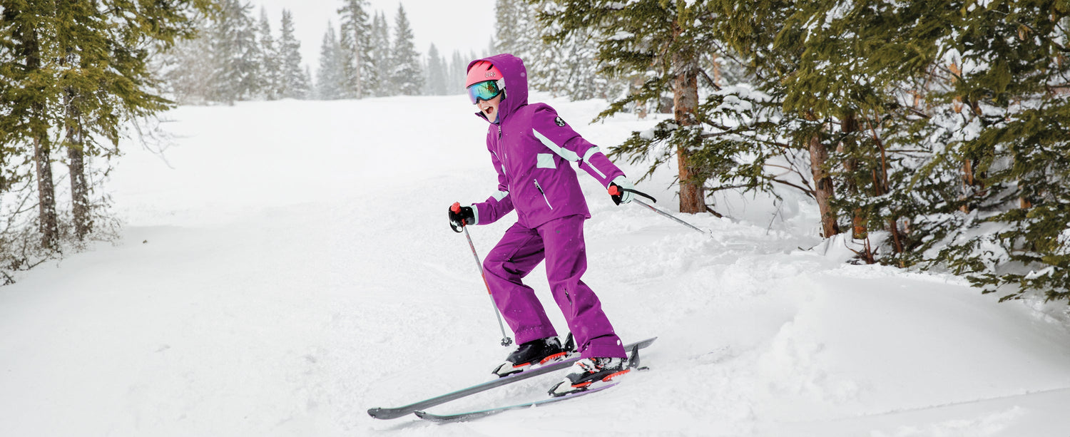 A teen girl skiing in Obermeyer through the trees.
