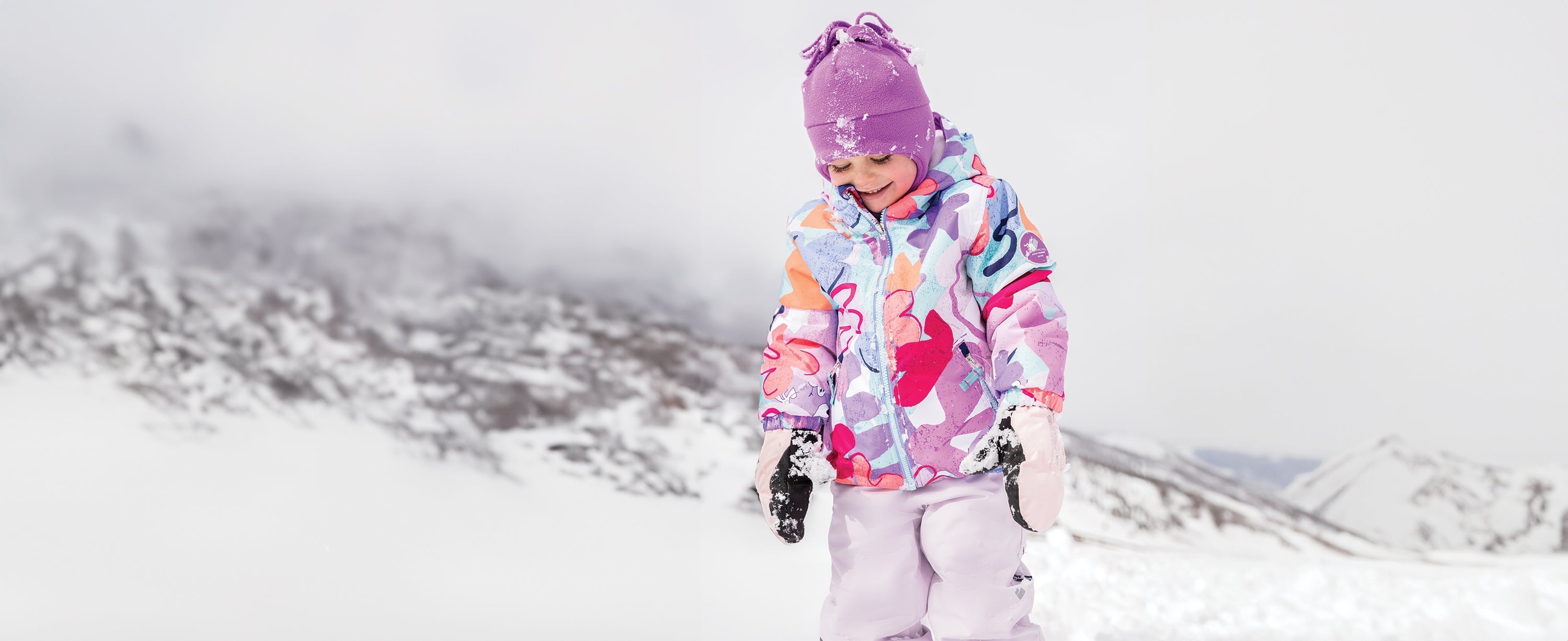 A little girl playing in the snow while wearing Obermeyer.