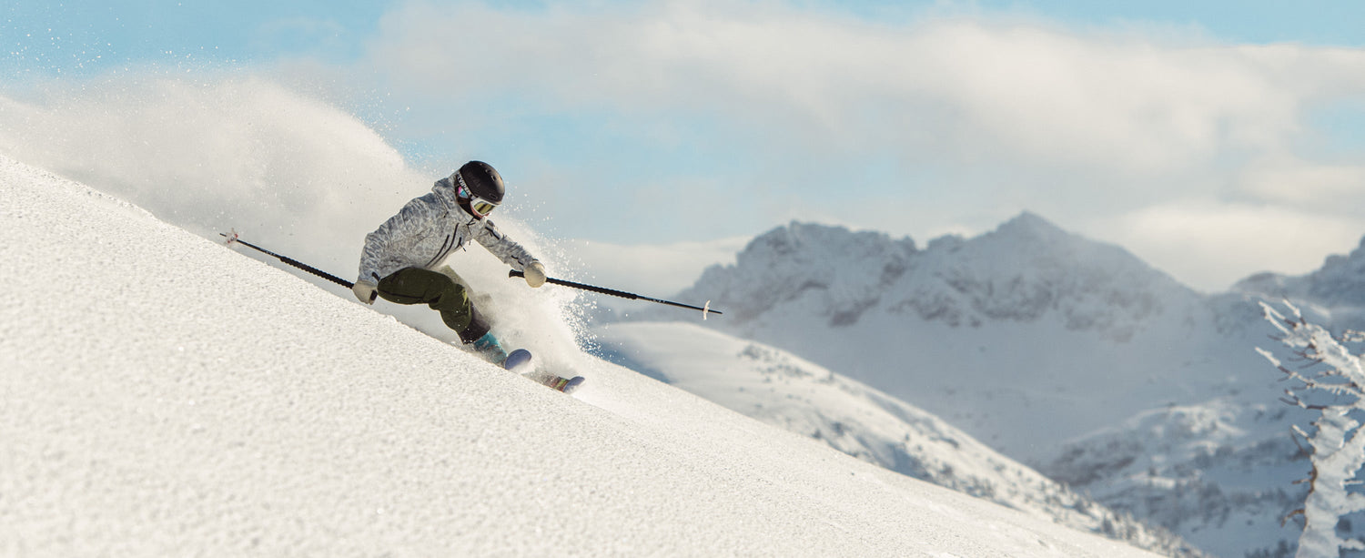 Skiier blowing fresh powder wearing an Obermeyer highlands shell jacket.