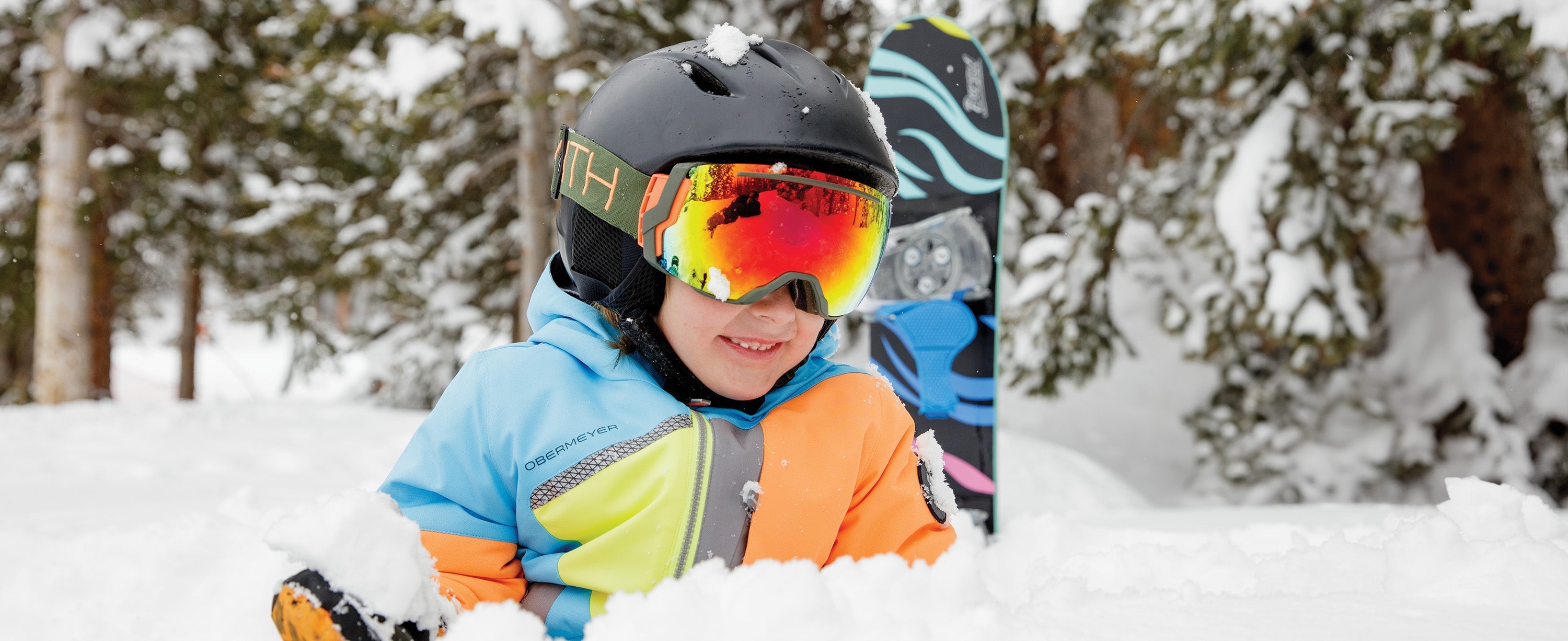 Kid boy and girl playing in the snow in Obermeyer ski apparel.