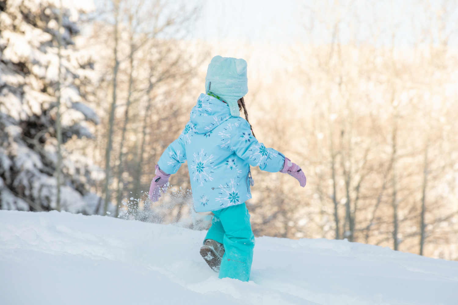 Two kids playing in the snow wearing Obermeyer.