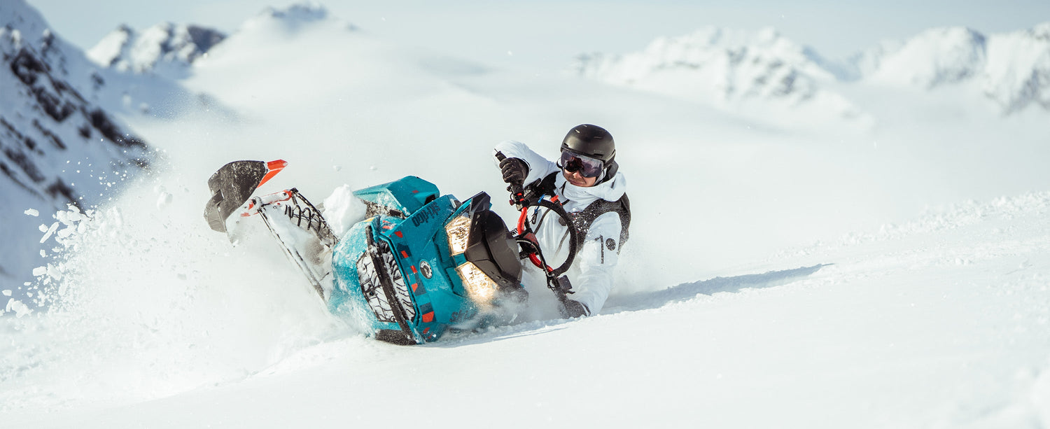 Male snowboarder riding a snowmobile in Alaska wearing Obermeyer apparel.
