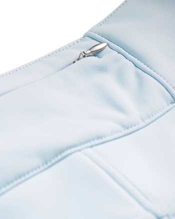 
Close-up detail of a light blue padded garment, showing stitched paneling and a small silver metal zipper pull.