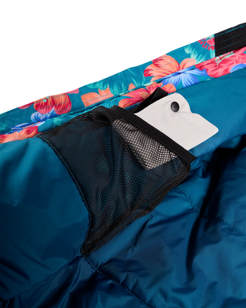 
Close-up of a teal blue puffer jacket showing a black mesh pocket with a white hangtag, alongside a colorful floral patterned trim.