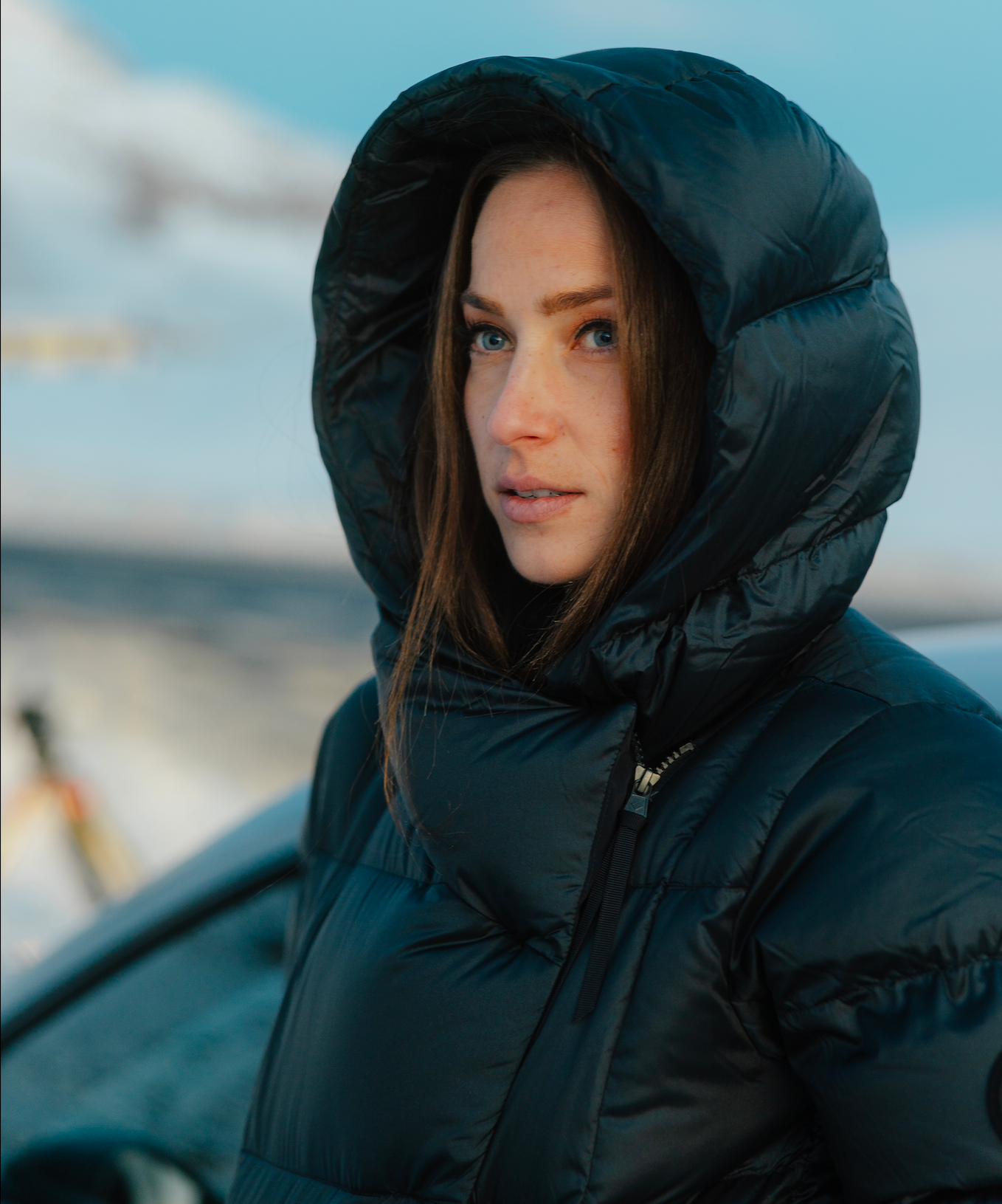 Person wearing a black puffer jacket with a hood in a snowy landscape